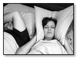 Woman holding pillow over ears to block sound of husband snoring and sleep apnea